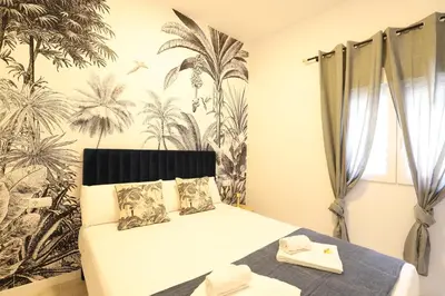 a bedroom with a bed and a palm tree wallpaper at Deslumbrante y familiar casa cerca de la playa in Puerto de Sagunto