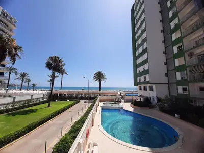 a swimming pool next to a building next to the beach at Apartamento Premium frente al mar, en primera linea de playa in Cullera