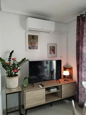 a living room with a television and a table at Ático Playa Cullera in Cullera