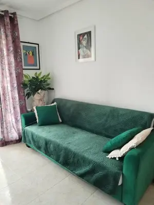 a green couch sitting in a living room at Ático Playa Cullera in Cullera