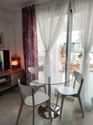 a dining room with a glass table and chairs and a window at Ático Playa Cullera in Cullera