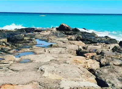 a group of people standing on the rocks on the beach at Magnífico piso con vistas al mar en Moncofa in Moncófar