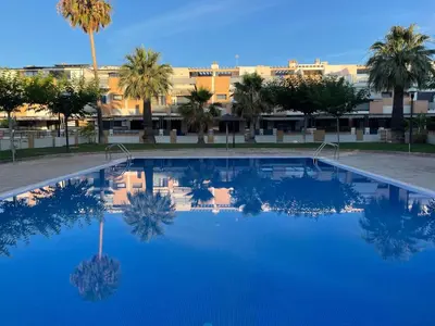 a large swimming pool with palm trees and a building at Valencia Sun House in Puebla de Farnals