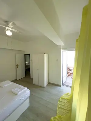a white room with a bed and a yellow chair at Mar y Puerto in Puerto de Sagunto