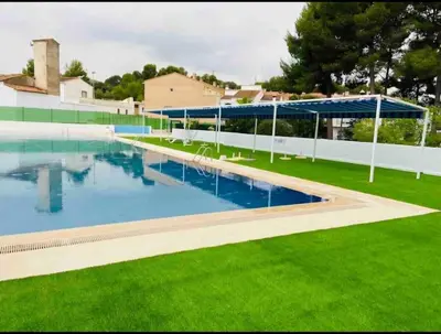 a large swimming pool with green grass next to a building at casa imperial in Tous