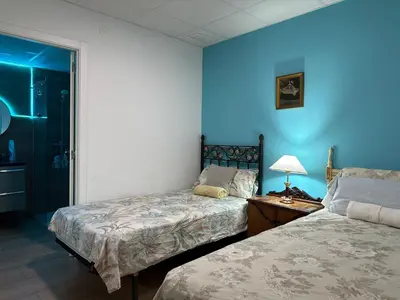 a bedroom with two beds and a blue wall at Mirador 5 del Mercado Central - habitacion con baño privado en el centro de la Ciudad Vella in Valencia