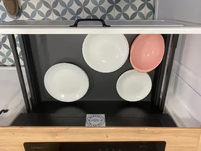four white dishes in a drawer of a microwave at ALZIRA BONiTA LES BARRAQUES LOFT in Alzira