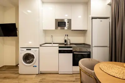 a kitchen with white cabinets and a washer and dryer at Cortes Suites by Concept Flats in Valencia