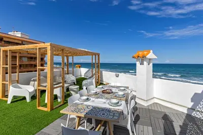 a patio with a table and chairs and the ocean at ViDa MaLu - Housevanlive in Sueca