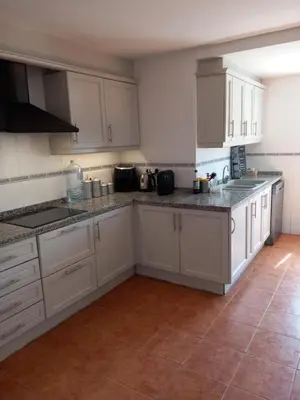 a kitchen with white cabinets and a tile floor at The Villarosa in Turís