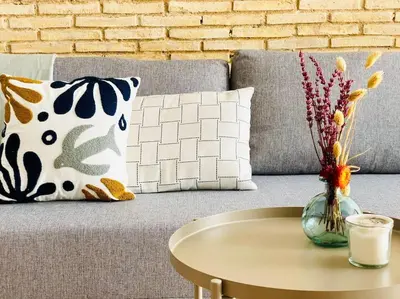 a couch with a table and a vase with flowers at BAJO A - Design & Comfort in Ruzafa SOHO in Valencia