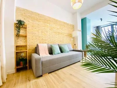 a couch in a living room with a brick wall at BAJO C - Design & Comfort in Ruzafa SOHO in Valencia