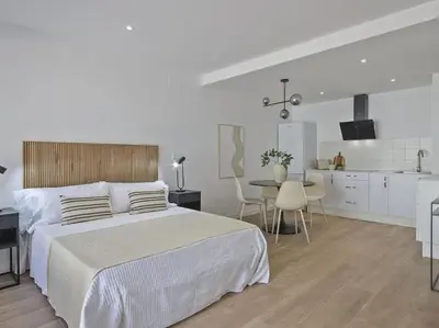 a white bedroom with a large bed and a kitchen at Estudio Temporal a 2' de la playa de Sagunto A2 in Puerto de Sagunto