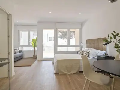 a white bedroom with a bed and a table and chairs at Estudio Temporal a 2' de la playa de Sagunto A2 in Puerto de Sagunto
