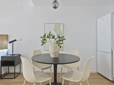 a dining room with a black table and white chairs at Estudio Temporal a 2' de la playa de Sagunto A2 in Puerto de Sagunto
