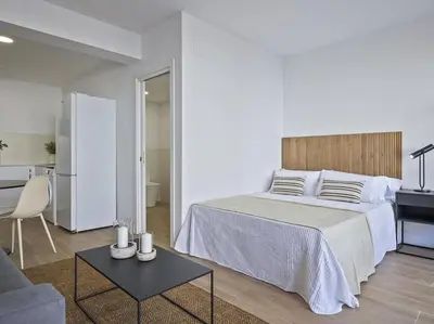 a white bedroom with a bed and a table at Moderno estudio a 2 minutos de la Playa Sagunto A3 in Puerto de Sagunto