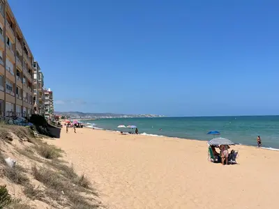 a group of people sitting on a beach with umbrellas at ESTUDIO CON JACCUZI Y SAUNA montaña y playa in Tavernes de Valldigna