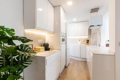 a white kitchen with white cabinets and a plant at UrbanNest Apartment in Valencia