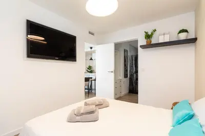a bedroom with a white bed with a flat screen tv at UrbanNest Apartment in Valencia