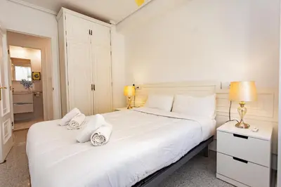 a white bedroom with a large white bed and two lamps at Cullera Horizon Apartment in Cullera