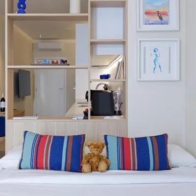 a teddy bear sitting on a bed with two pillows at Osito Hub - Justo y Pastor in Valencia