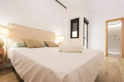a white bedroom with a large bed with white sheets at Roca 26 in Valencia