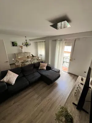 a living room with a black couch and a table at Departamento en Torrent in Torrent