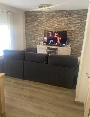 a black couch in a living room with a tv at Departamento en Torrent in Torrent