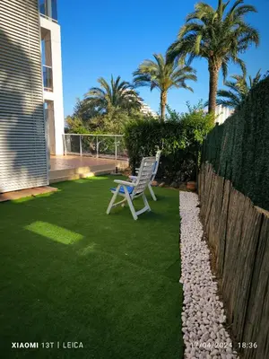 a white chair sitting on a lawn next to a fence at Apartamento Masia Racó Cullera in Cullera