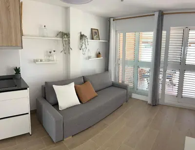a living room with a gray couch and windows at vivienda independiente in Canet de Berenguer
