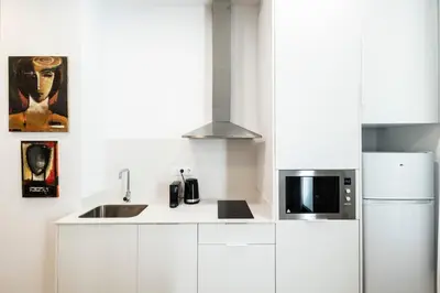 a white kitchen with a sink and a microwave at La casa de la pintora by Concept Flats in Valencia