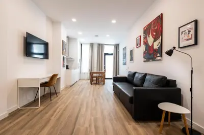 a living room with a black couch and a desk at La casa de la pintora by Concept Flats in Valencia