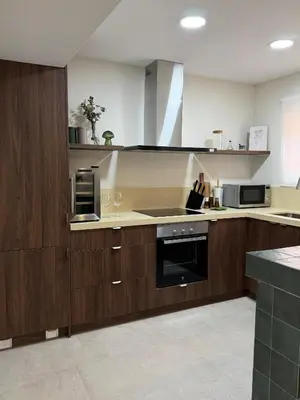 a kitchen with wooden cabinets and a stove top oven at Apartamento con increíbles vistas a la bahía de Cullera in Faro de Cullera