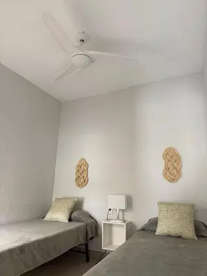 a bedroom with two beds and a ceiling fan at Apartamento con increíbles vistas a la bahía de Cullera in Faro de Cullera