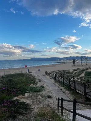 a path on a beach with a fence and the ocean at Apartamento con increíbles vistas a la bahía de Cullera in Faro de Cullera