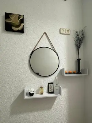 a mirror hanging on a wall with a shelf at Acogedora planta baja in Benaguacil