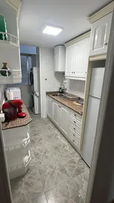 a kitchen with white cabinets and a tile floor at Apartments del sol in Cullera
