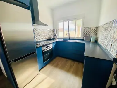a kitchen with blue cabinets and a stainless steel refrigerator at El Riuet-Chalet apartamento a 1 minuto de la playa, Cullera in Cullera