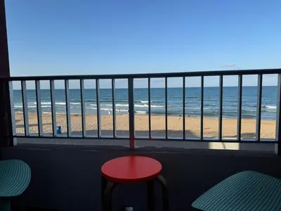 a view of the beach from a balcony with a red stool at Valencia Frente al mar in Valencia