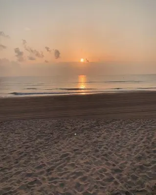 a beach with the sun setting on the ocean at Valencia Frente al mar in Valencia