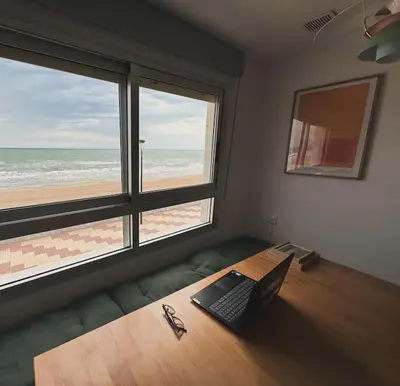 a room with a laptop on a table with a beach at Valencia Frente al mar in Valencia