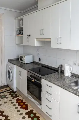 a kitchen with white cabinets and a sink and a dishwasher at Habitación Maritim 1 in Valencia