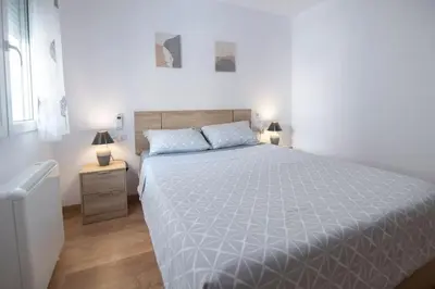 a white bedroom with a large bed and two lamps at Piso Reformado Cerca de la Playa y de Valencia Ciudad en el Barrio de San Antonio in Cullera