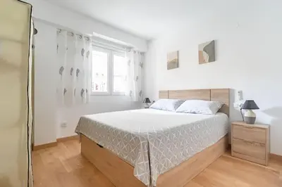 a white bedroom with a large bed and a window at Piso Reformado Cerca de la Playa y de Valencia Ciudad en el Barrio de San Antonio in Cullera