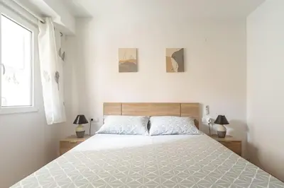 a white bedroom with a large bed and a window at Piso Reformado Cerca de la Playa y de Valencia Ciudad en el Barrio de San Antonio in Cullera