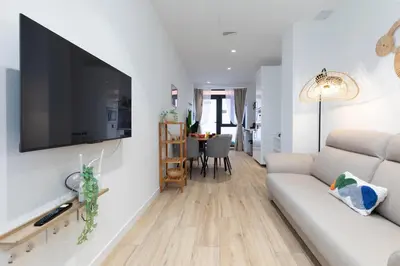 a living room with a couch and a television on a wall at Travel Habitat Marítim-Serrería Lofts in Valencia