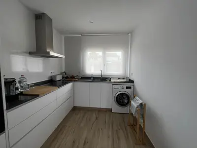 a white kitchen with a washing machine in it at Acogedora casa con piscina in Lliria