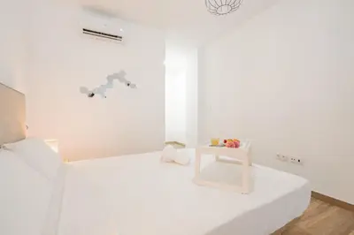 a white bedroom with a white bed with a white table at VisitVal Flats 3 in Valencia