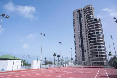 a tennis court in front of a tall building at Espacio2,1a línea,jacuzzi,piscina in Cullera