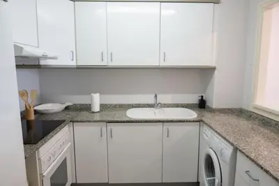 a white kitchen with a sink and a dishwasher at Espacio2,1a línea,jacuzzi,piscina in Cullera